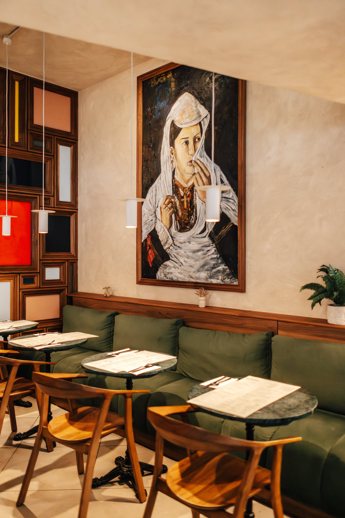Green banquettes and marble tables inside Fiena cafe bar and restaurant, King's Cross